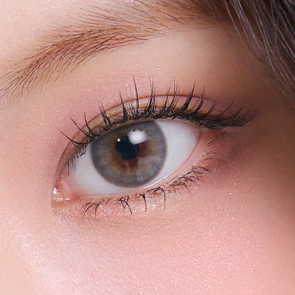 Macro shot of an unpackaged colored contact lens design: a three-tone pattern featuring a bright yellow-gold inner ring, a medium warm hazel color, and a black limbal ring.