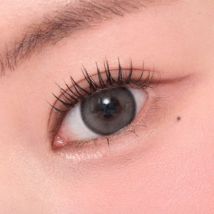 Model wearing OLENS Realish Gray monthly colored contacts for a cool toned subtle half-eye look